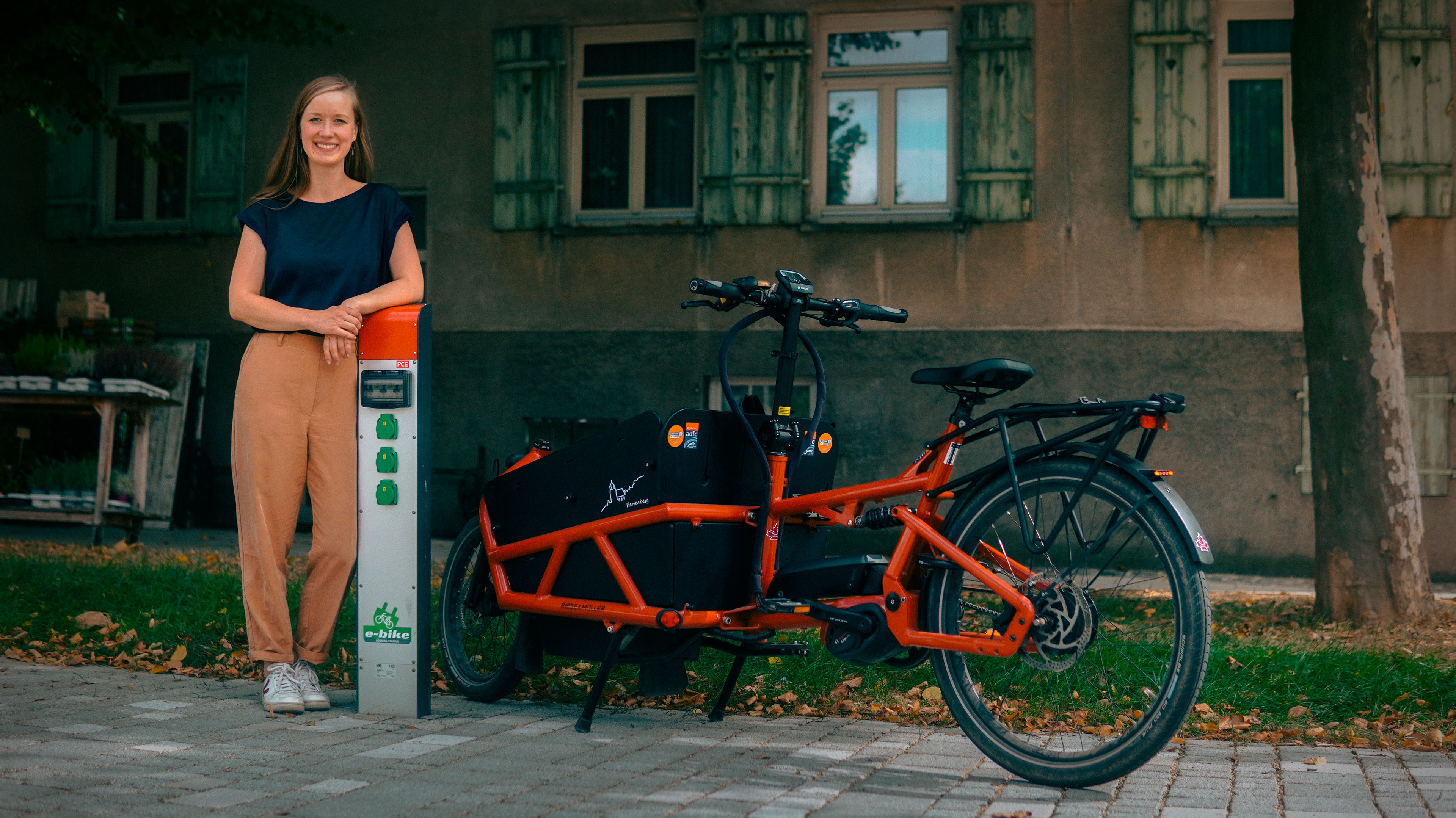 Projektmanagerin Jana Zieger gewann im Jahr 2022 mit dem stadtnavi Herrenberg bei "Wir machen Mobilitätswende". Auf dem Bild ist sie neben einem Lastenrad zu sehen. Oben rechts steht der Hinweis, dass die Bewerbungsfrist bis 12.04.2025 verlängert wurde.