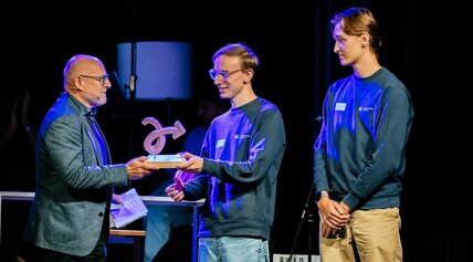 Verkehrsminister Hermann übergibt die Trophäe für die Kategorie Kommunikation an zwei junge Männer.