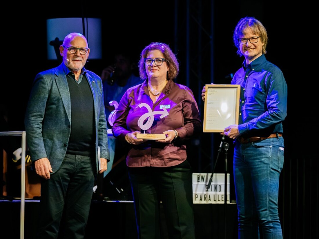 Verkehrsminister Hermann, eine Frau und ein Mann, zusammen auf der Bühne mit der Trophäe für die Kategorie Garantiert Mobil. 