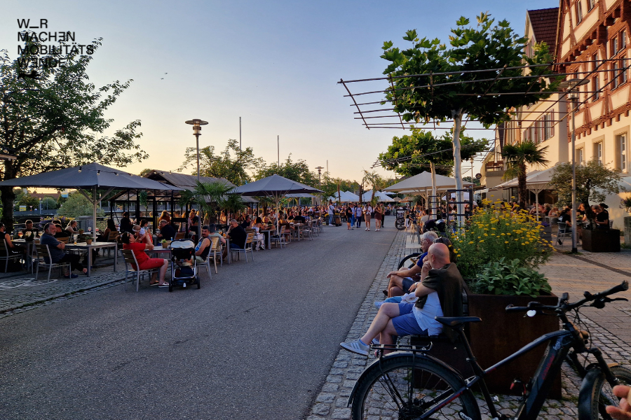 Eine belebte Ortsmitte mit Sonnenschirmen, Sitzmöglichkeiten und Personen in Nürtingen.