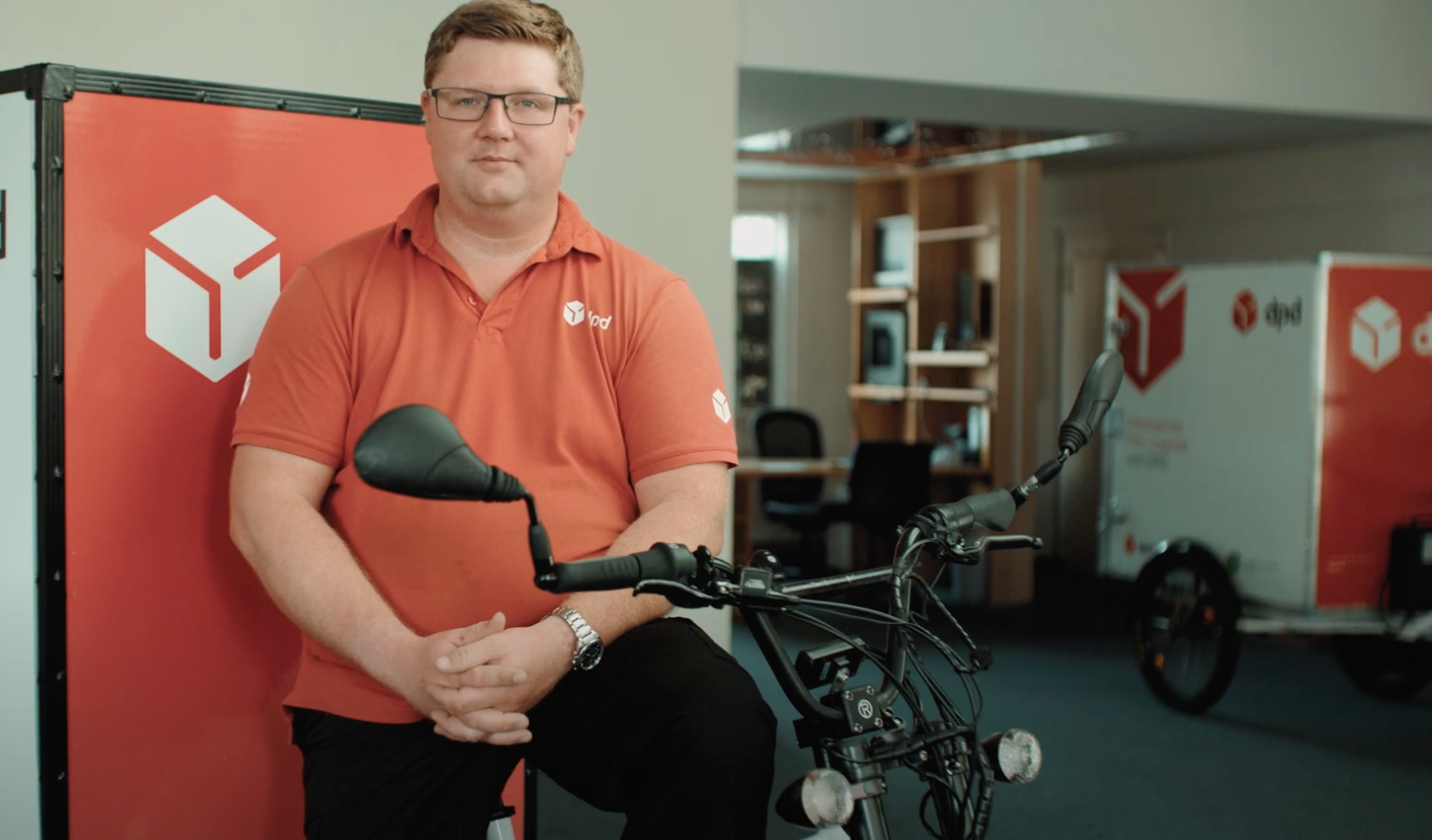 Ein Mann in Arbeitskleidung der auf seinem Rad posiert. 