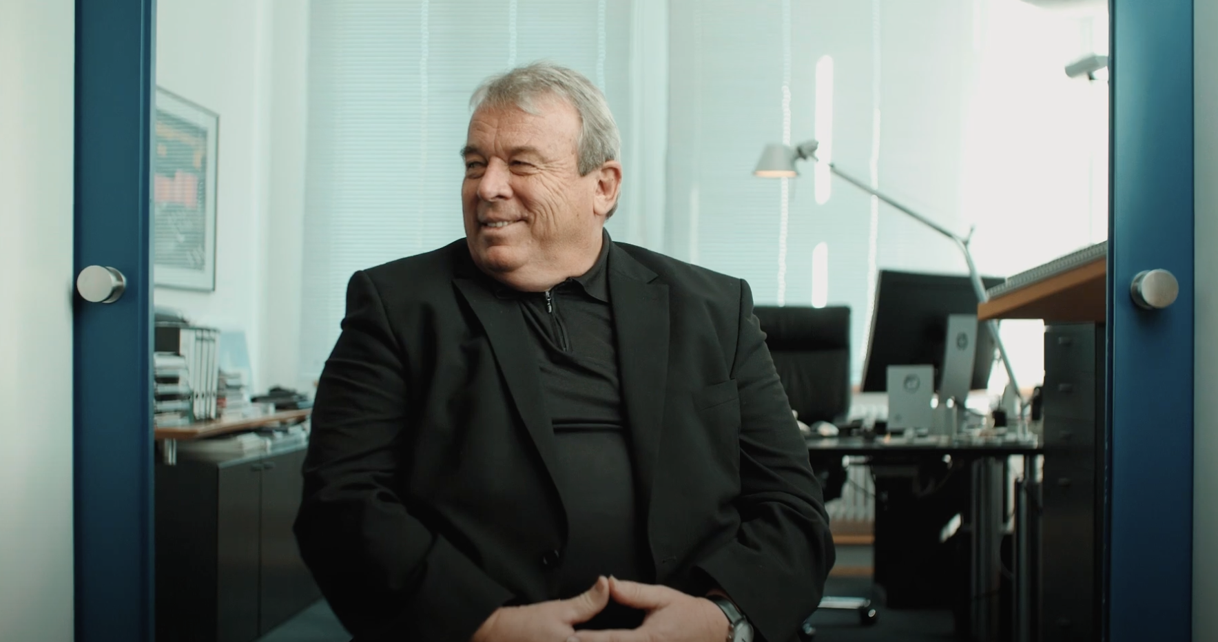 Mann mit Anzug der zur Seite blickt sitzt in einem Büro.