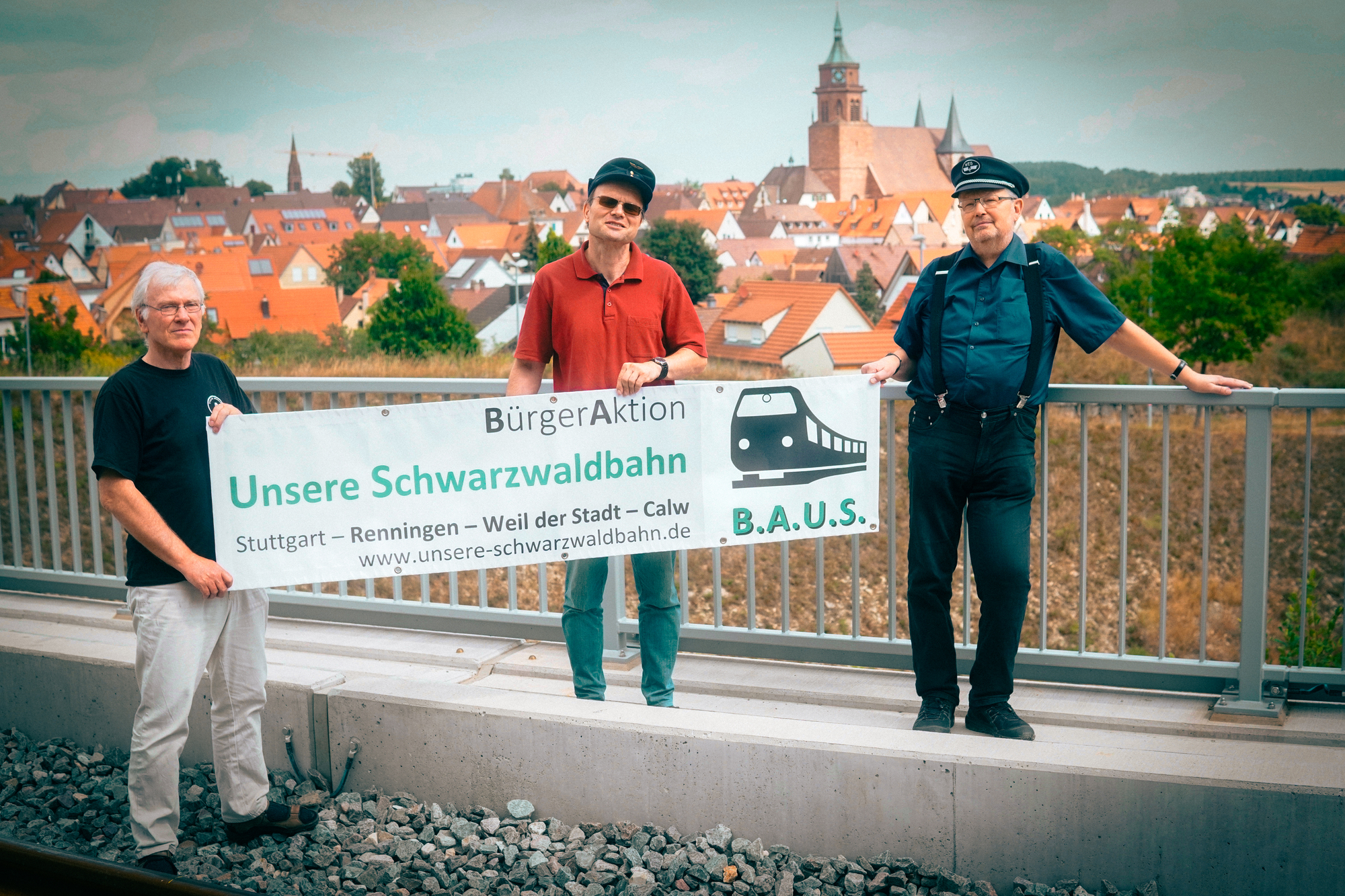 Drei Personen die ein Banner in der Hand halte und auf einem Flachdach stehen, im Hintergrund ist eine Stadt zu sehen
