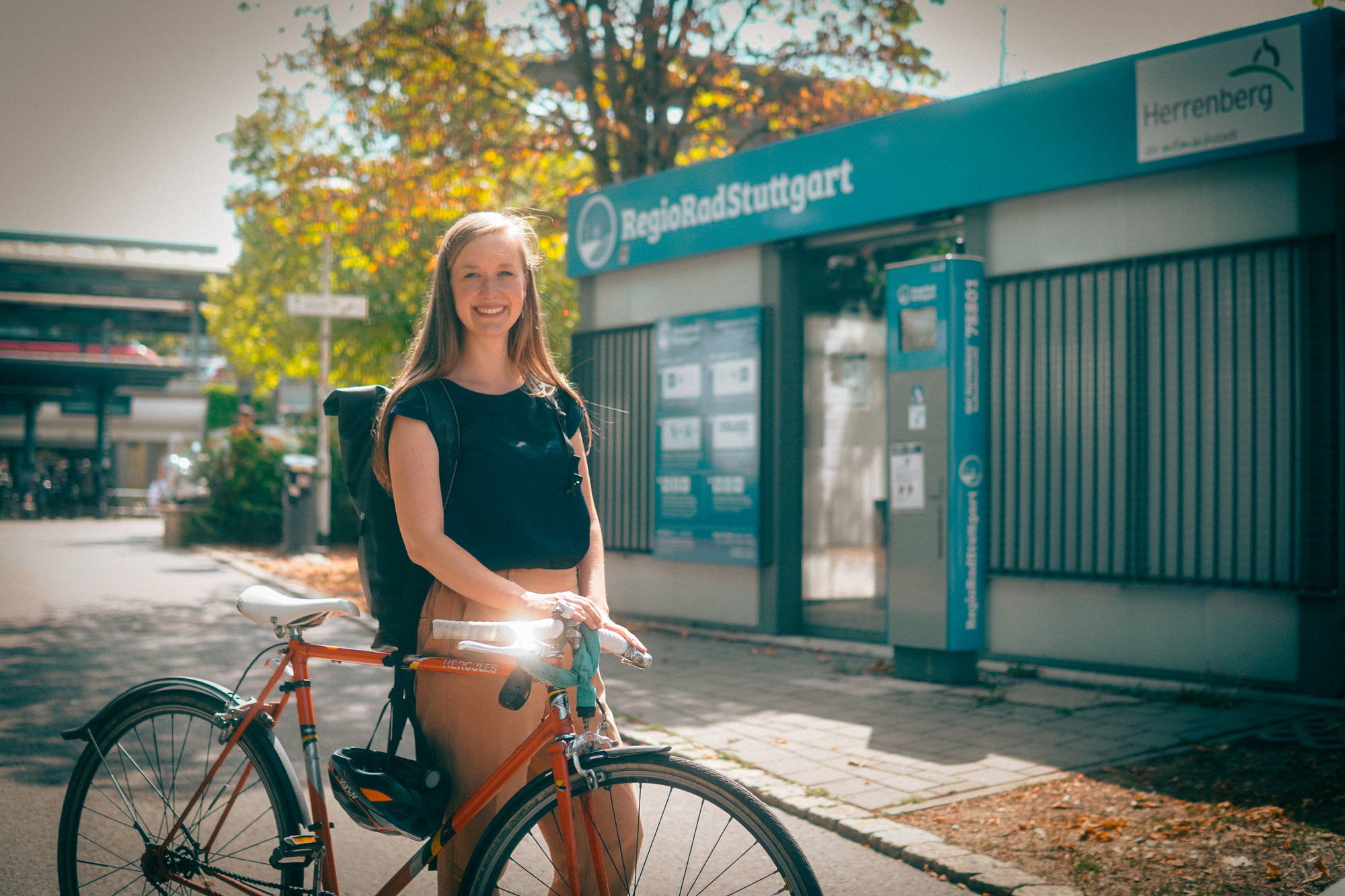 Eine Frau schiebt ihr Fahrrad bei schönem Wetter über die Straße.