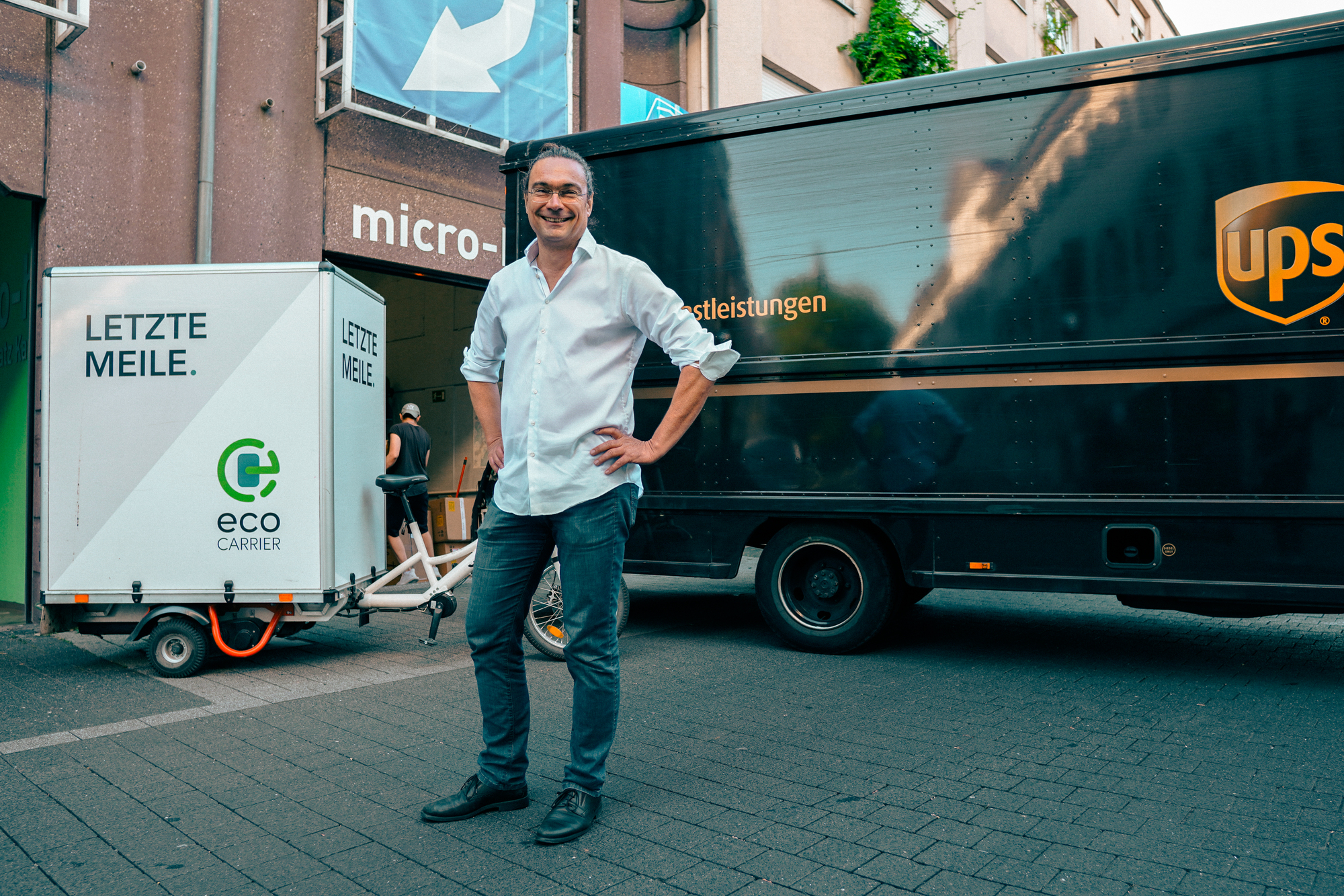 Ein Mann steht vor einem UPS Paketwagen und einem Fahrrad mit Anhänger.