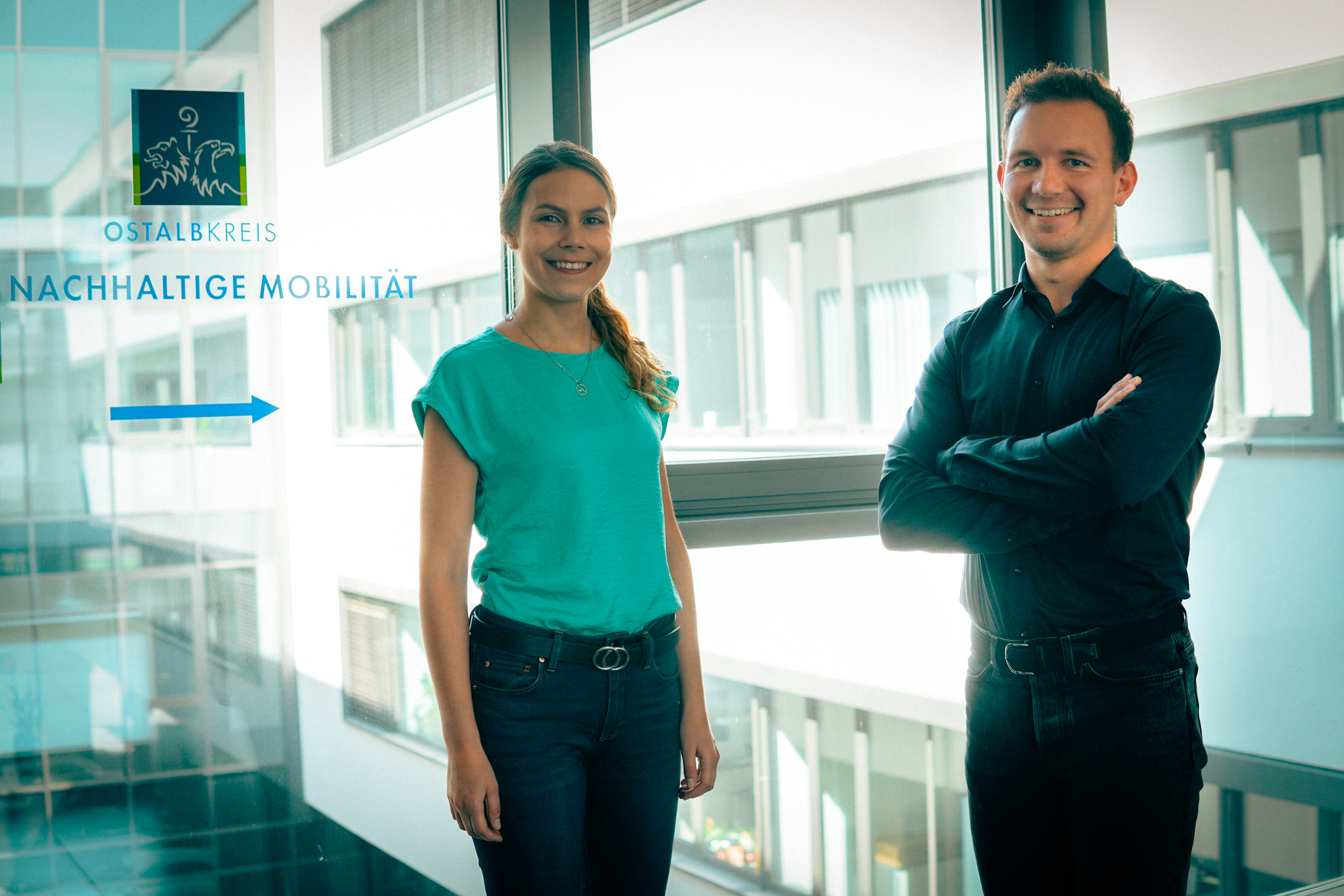 Eine Frau und ein Mann stehen in einem Gebäude vor einer großen Fensterscheibe.