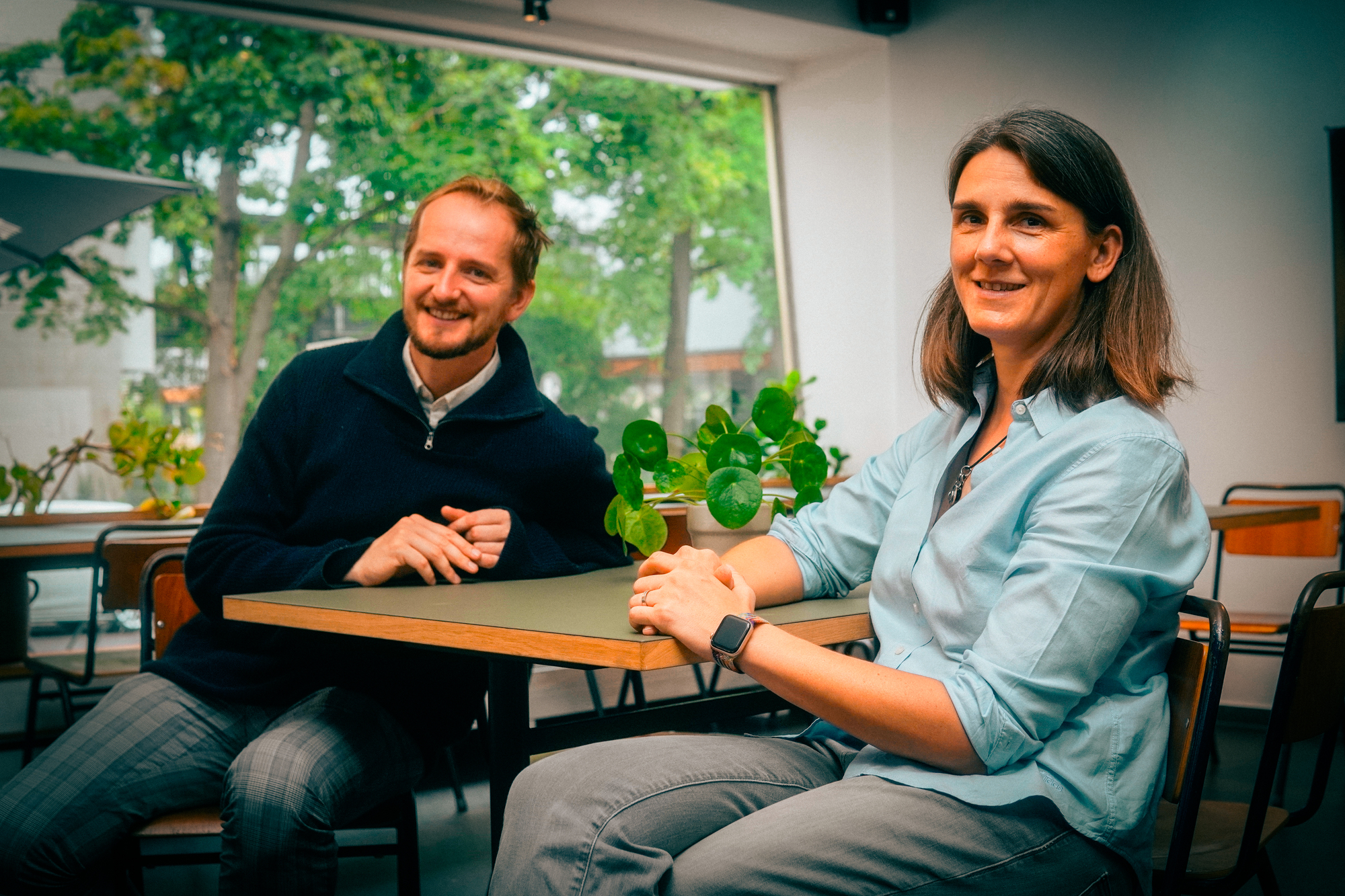 Eine Frau und ein Mann die an einem Tisch in einem Innenraum sitzen.